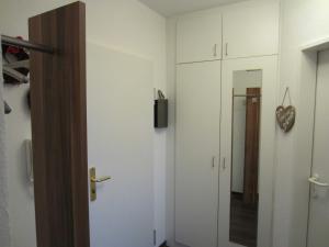 Zimmer mit weißen Schränken und einer Tür mit Spiegel in der Unterkunft Ferienwohnung Ingeborg in Kühlungsborn