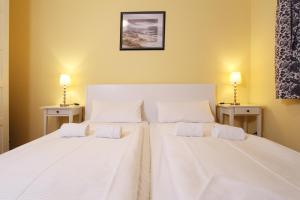 2 weiße Betten in einem Zimmer mit 2 Lampen in der Unterkunft Ferienwohnung Meeresblick in Kühlungsborn