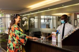 a woman standing at a counter with a man wearing a mask at The Hyde All Suite Hotel in Cape Town +80 photos