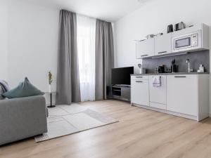 a white living room with a couch and a kitchen at limehome Rosenheim Gillitzerstraße in Rosenheim