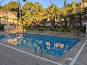 einen Pool in einem Hotel mit Palmen und einem Gebäude in der Unterkunft Apartamento Cala del Pi in Platja  d'Aro