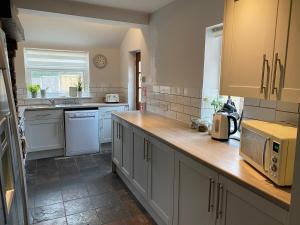 uma cozinha com armários brancos e um balcão com um micro-ondas em Newlyn House - Sleeps 11 em Chester