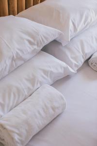 a pile of white pillows on a bed at MUTE Hostel Porto Covo in Porto Covo