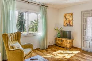 een woonkamer met een stoel en een televisie bij Apartamento Bajo 1 in Begur