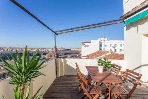 un patio con tavolo e sedie in legno sul balcone. di Ático céntrico confortable y luminoso a Madrid