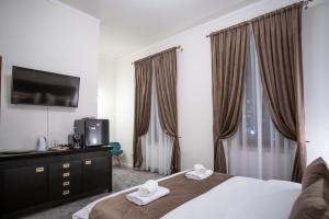 Schlafzimmer mit einem Bett, einem TV und Vorhängen in der Unterkunft The Nest Baia Mare in Baia Mare