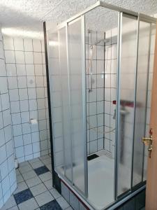 a glass shower in a white tiled bathroom at Ferienwohnung Palm in Monschau +30 photos