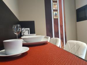 uma mesa vermelha com pratos brancos e um copo de vinho em Kaposvár Apartman em Kaposvár