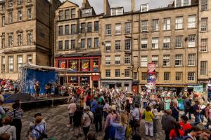 una multitud de personas de pie en una calle frente a los edificios en Stunning Panoramic Views: Heart of the Royal Mile, en Edimburgo