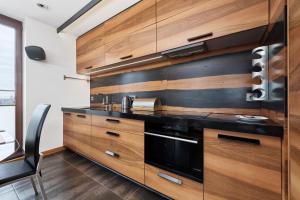a kitchen with wooden cabinets and a black oven at Luxurious Apartments Walonska with underground GARAGE by Renters in Wrocław