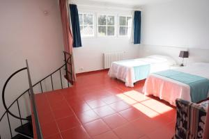 a room with two beds and a red tile floor at Orquideas in Cala Galdana