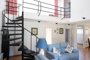 a living room with a blue couch and a spiral staircase at Orquideas in Cala Galdana
