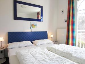 a bedroom with a bed with a blue headboard and a mirror at Ferienwohnung Waldblick Nr. 17 in Kühlungsborn