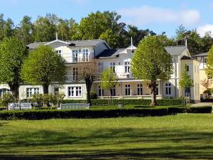 una grande casa bianca con alberi di fronte di Ferienwohnung Seeadler Nr. 8 a Kühlungsborn