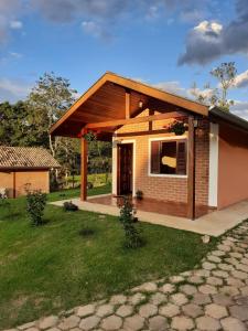 een klein huis met een patio en een tuin bij Encanto das Rosas in Santo Antônio do Pinhal