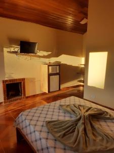 a room with a bed and a tv on the wall at Encanto das Rosas in Santo Antônio do Pinhal