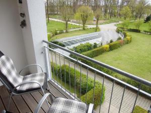 einen Balkon mit 2 Stühlen und Gartenblick in der Unterkunft Ferienwohnung Sonnenschein - direkte Meerlage in Kühlungsborn