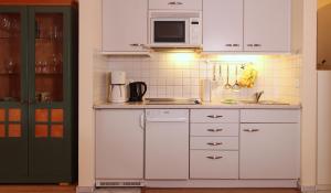 eine Küche mit weißen Schränken und einer Mikrowelle in der Unterkunft Ferienwohnung Parkblick Nr. 22 in Kühlungsborn