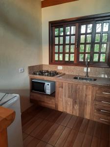 a kitchen with a sink and a microwave at Encanto das Rosas in Santo Antônio do Pinhal