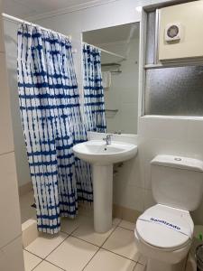 y baño con aseo blanco y lavamanos. en Villa del Rio Express en Valdivia