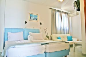 Dormitorio azul y blanco con cama y sofá en Domna Studios, en Lindos