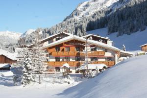 a ski lodge in the snow in front of a mountain at Appartementhaus Holiday in Lech am Arlberg