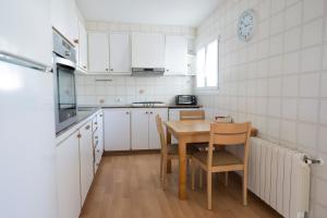 a kitchen with white cabinets and a table and chairs at Orquideas in Cala Galdana