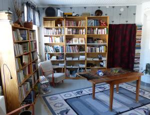 ein Zimmer mit einem Tisch und Bücherregalen mit Büchern in der Unterkunft Lugnet i Oslättfors in Gävle