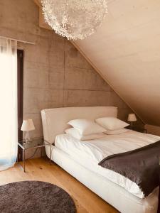 una camera da letto con un grande letto bianco e un lampadario a braccio di Hotel de l’Ours Preles a Prêles