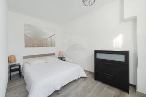 - une chambre avec un lit et une commode avec une télévision dans l'établissement AS15280 - P3 face à la mer avec garage privé à 2 pas du Centre Ville, au Grau-du-Roi