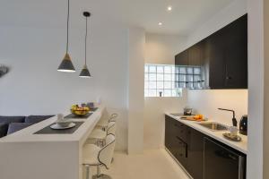 a kitchen with black cabinets and a white counter top at Penthouse & apartments by the Sea airport Airstay in Artemida