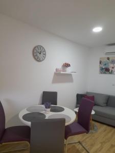 ein Wohnzimmer mit einem Tisch, Stühlen und einer Uhr in der Unterkunft Apartment Lena in Gornji Vaganac