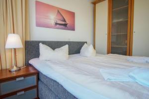 ein Schlafzimmer mit einem großen weißen Bett mit einer Lampe in der Unterkunft "Strandhotel Heiligenhafen", Wohnung 126 in Heiligenhafen