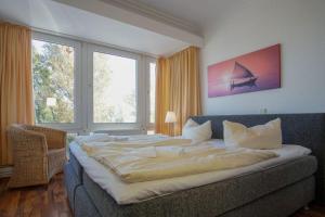 ein großes Bett in einem Zimmer mit einem großen Fenster in der Unterkunft "Strandhotel Heiligenhafen", Wohnung 126 in Heiligenhafen