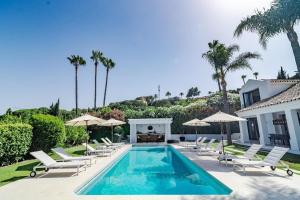 - une piscine avec des chaises et des parasols à côté d'une maison dans l'établissement Villa Tuscany, à Marbella