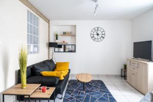 a living room with a black couch and a tv at Le 4midable - Chaleureux 2 pièces in Bouguenais