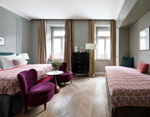 a hotel room with two beds and a table and chairs at numa l Mozart in Salzburg