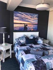 a bedroom with a bed with a painting on the wall at Modern Apartment walking distance to Main Beach Restaurants and other amenities in Jeffreys Bay