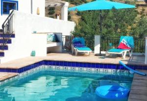 a swimming pool with two chairs and an umbrella at Algarrobo Azul in Almuñécar