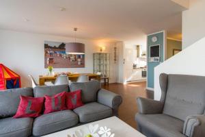 - un salon avec un canapé gris et des oreillers rouges dans l'établissement Ferienhaus-Luv, à Heiligenhafen