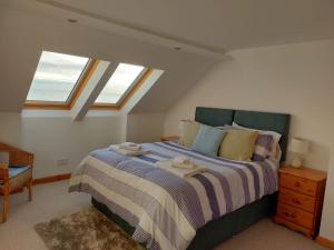 a bedroom with a large bed with two windows at Gowan Bank in Gourdon