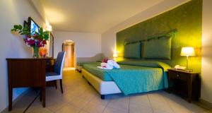 a bedroom with a bed with a table and a desk at Elihotel in SantʼAlessio Siculo