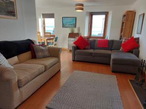 uma sala de estar com 2 sofás e almofadas vermelhas em Gowan Bank em Gourdon
