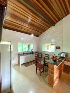 Una cocina con un refrigerador y una mesa dentro. en Suite Confortavel em Chapada dos Guimaraes, en Chapada dos Guimarães