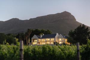 une grande maison avec une montagne en arrière-plan dans l'établissement Banhoek Lodge, à Stellenbosch
