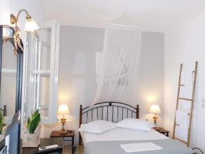 1 dormitorio con 1 cama con sábanas blancas y 2 lámparas en Alezina studios, en Amorgós