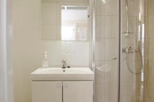 y baño blanco con lavabo y ducha. en Topcamp Havblikk - Helgeland, en Nesna