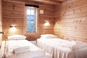 two beds in a room with wooden walls at Topcamp Havblikk - Helgeland in Nesna