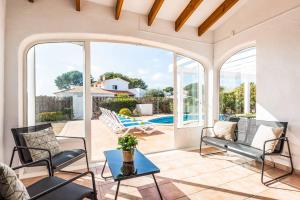 a patio with chairs and a table and a pool at Villa Mimosa in Binibeca