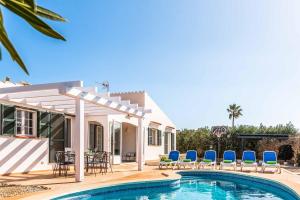 a villa with a swimming pool and blue chairs at Villa Mimosa in Binibeca